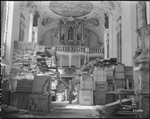Foto del 24 aprile 1945: un soldato americano della Terza Armata, sovrastato da una montagna di oggetti d’arte rubati dai nazisti e stoccati in una chiesa a Ellingen, in Germania. Courtesy The National Archives